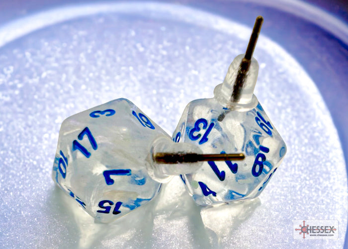 Two clear dice with blue numbers on a reflective surface, featuring the Chessex brand.