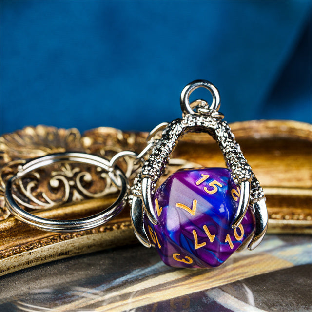 Purple polyhedral die keychain with silver metalwork on a reflective surface with a blue background