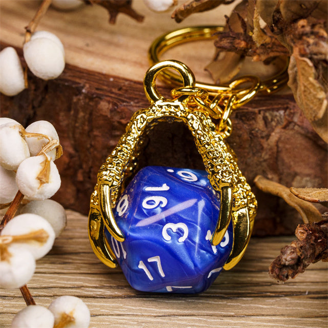 Blue polyhedral die in a gold dragon's claw on a wooden surface with decorative elements.