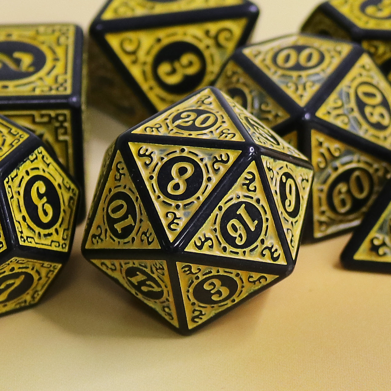 Gold and black polyhedral dice set on a beige surface