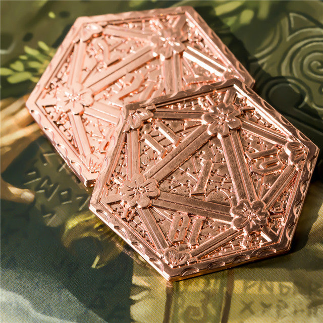 Decorative rose gold compact mirror with intricate patterns on a green surface