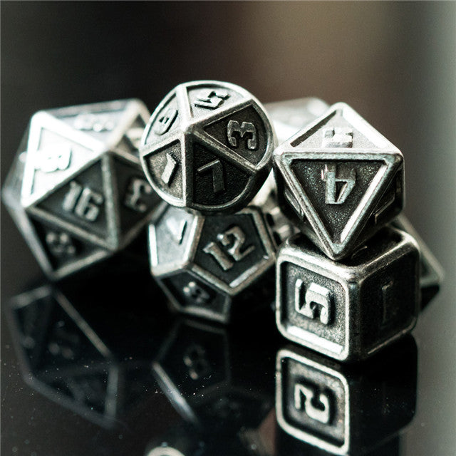 Set of metallic polyhedral dice on a reflective surface with a dark background