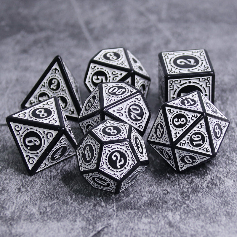 Set of black and silver polyhedral dice on a gray surface