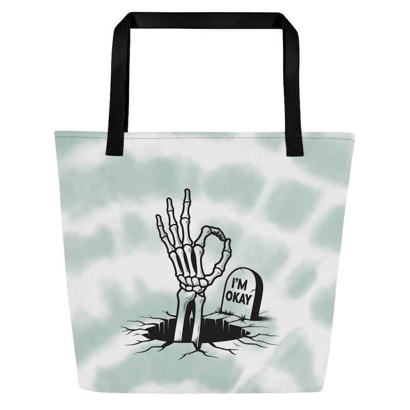 Tote bag with skeleton hand and 'I'm Okay' gravestone design on a tie-dye background