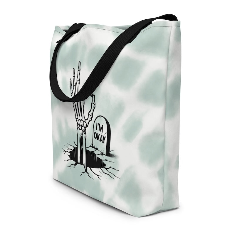 Tote bag with skeleton hand and 'I'm Okay' gravestone design on a light background