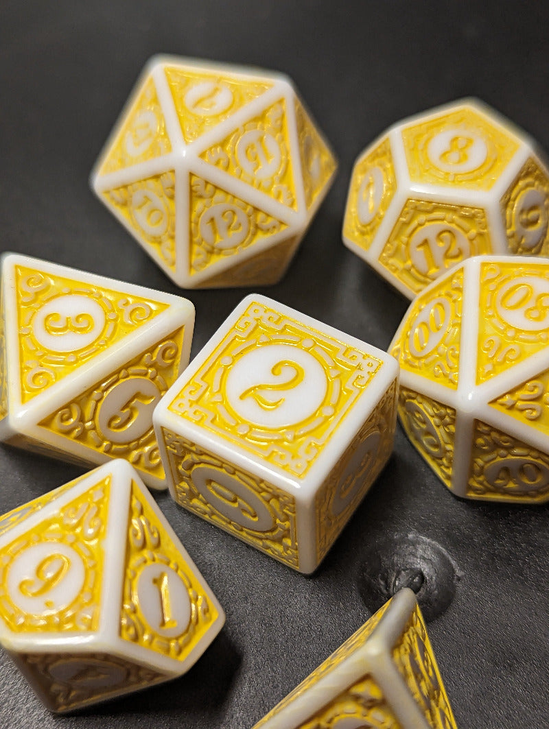 Set of yellow and white polyhedral dice on a dark surface