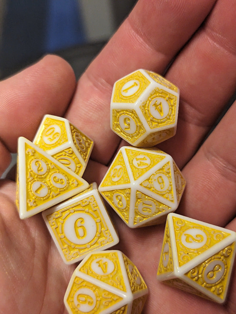 Set of yellow and white polyhedral dice held in a hand