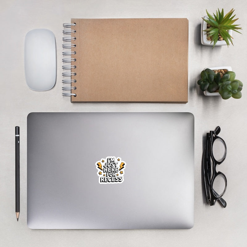 Laptop with a sticker, notebook, mouse, pencil, glasses, and plants on a light surface