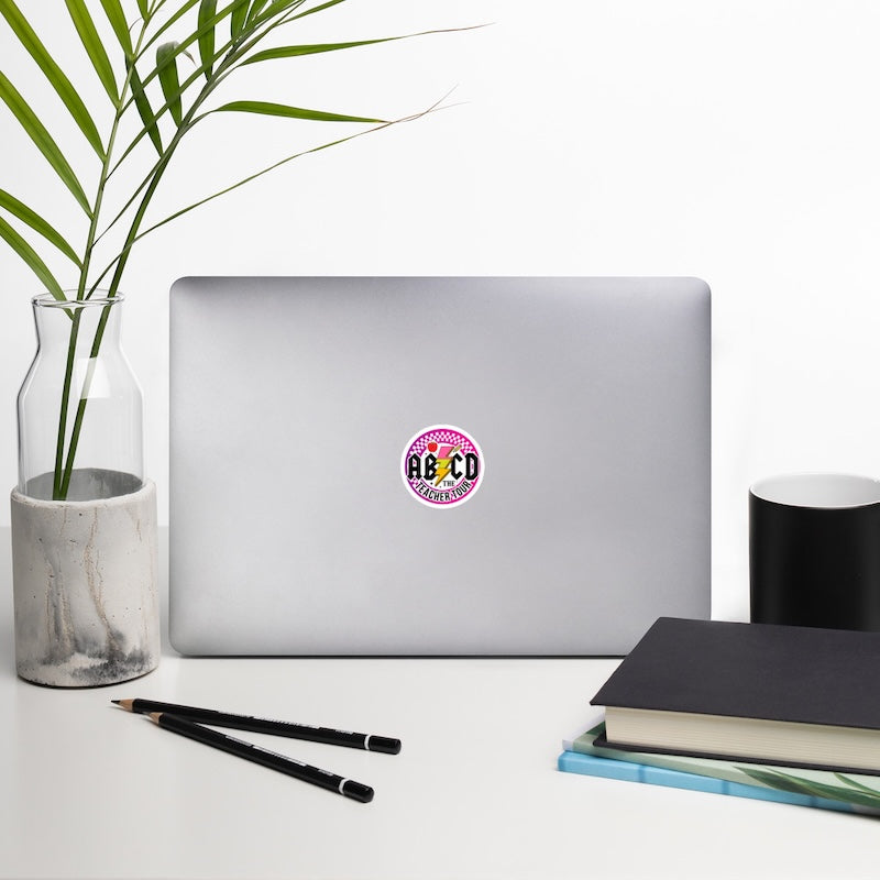 Laptop with a colorful sticker on a desk with a plant, pencils, and books.