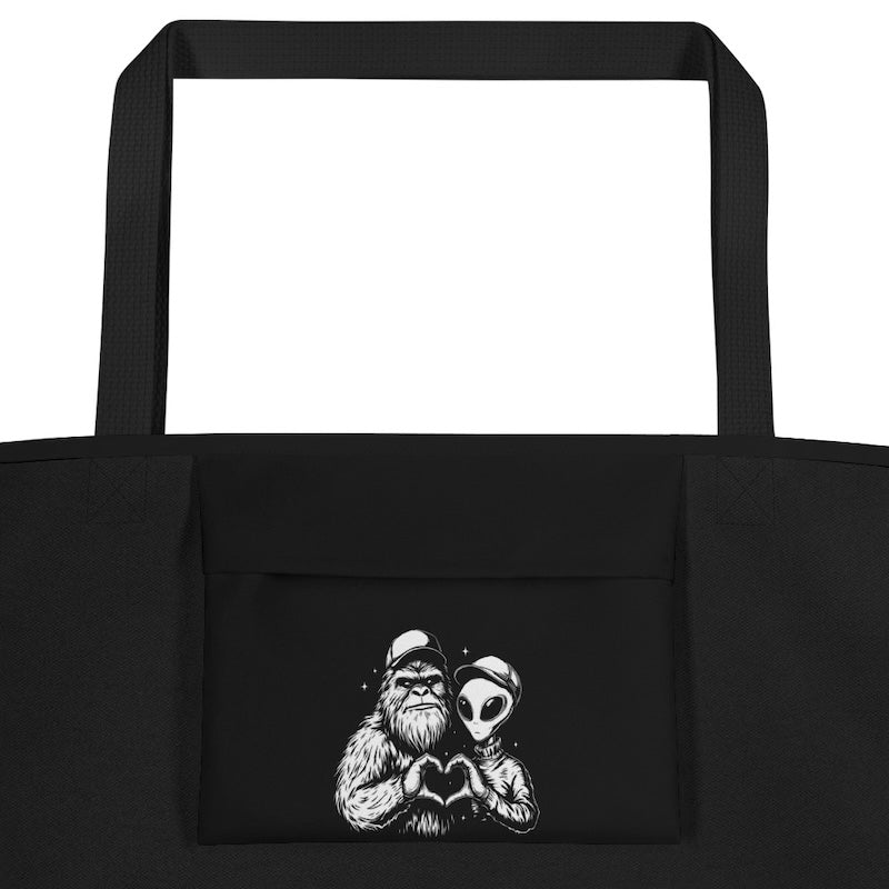Black tote bag with a graphic of a bearded person and an alien holding hands on a white background