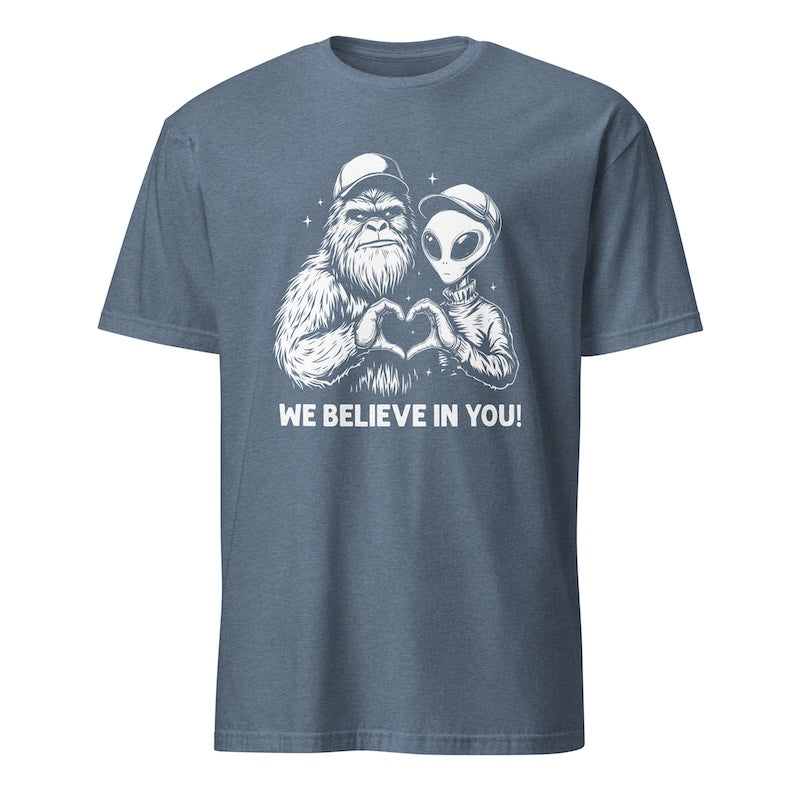 Blue t-shirt with a graphic of a creature and alien making a heart shape and text 'WE BELIEVE IN YOU!' on a white background.