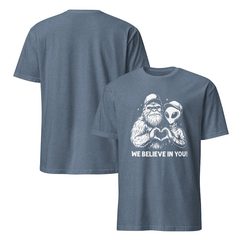 Blue t-shirt with a graphic of a Sasquatch and alien holding hands, with text 'WE BELIEVE IN YOU!' on a white background.