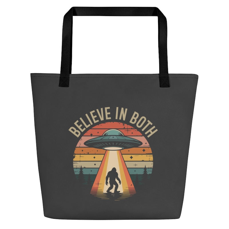 Black tote bag with UFO and Bigfoot design and 'Believe in Both' text on a white background
