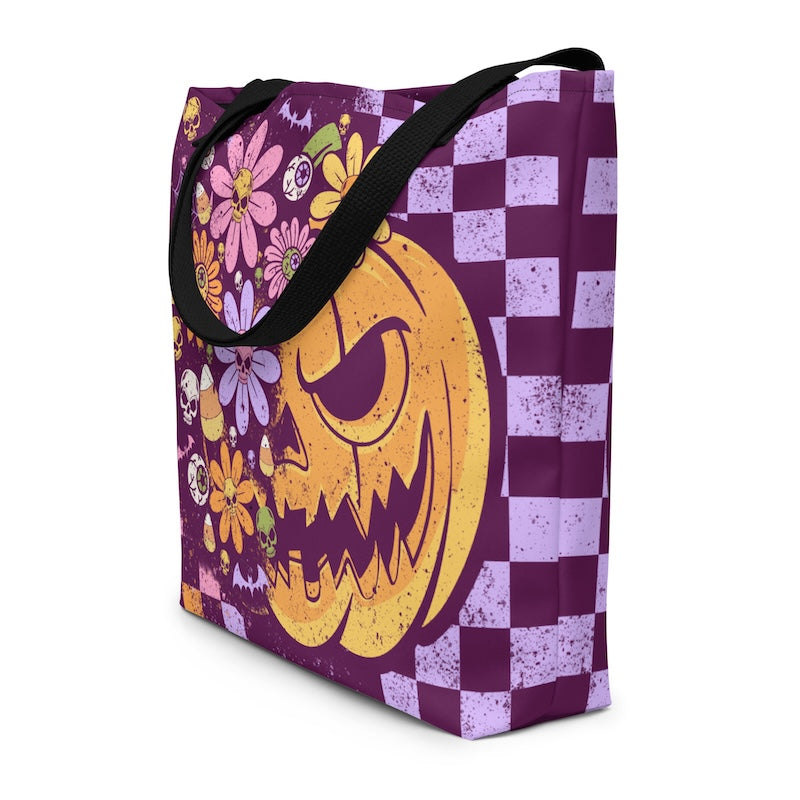 Tote bag with Halloween design featuring a pumpkin face and flowers on a purple and white checkered background.