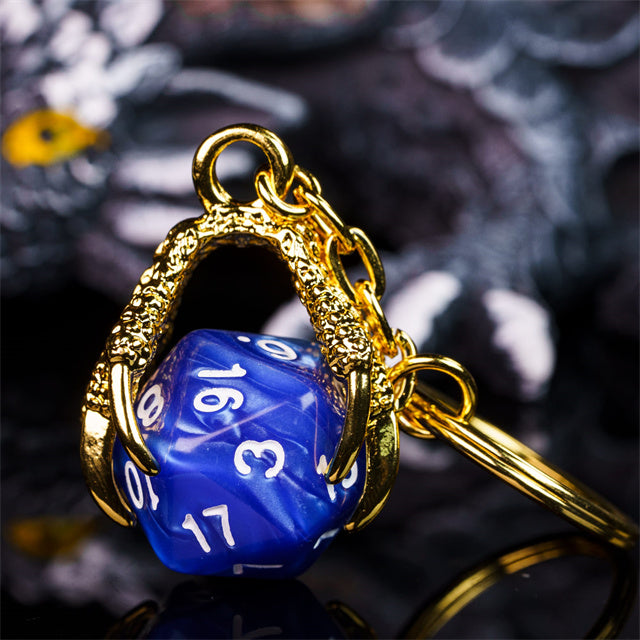 Blue die-shaped keychain with gold chain on a dark background