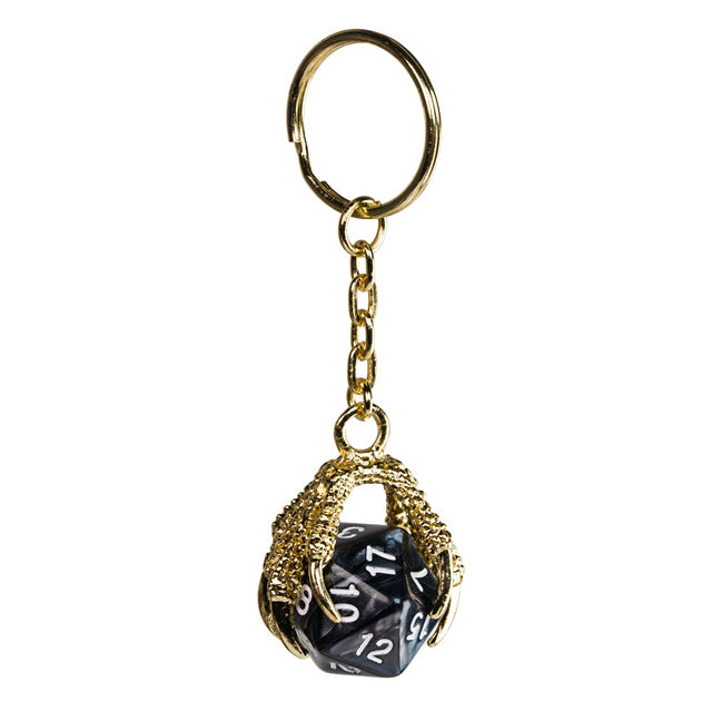 Keychain with a black die inside a gold cage on a white background