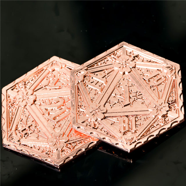 Decorative rose gold metal object with intricate designs on a black background
