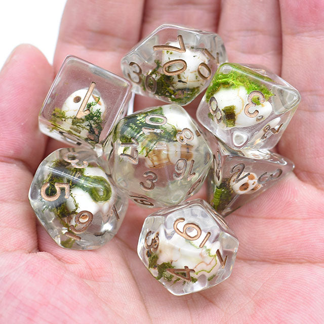 Set of clear dice with greenery and gold text held in a hand