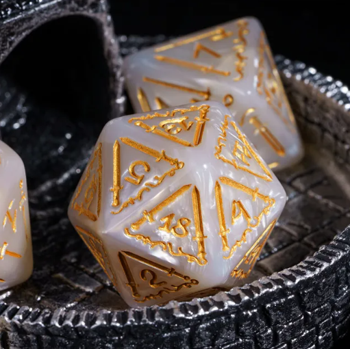 White dice with gold numbering on a textured black surface