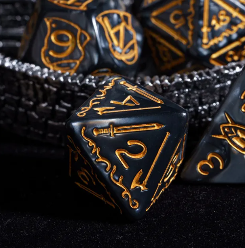 Black dice with gold numbering and symbols on a dark background