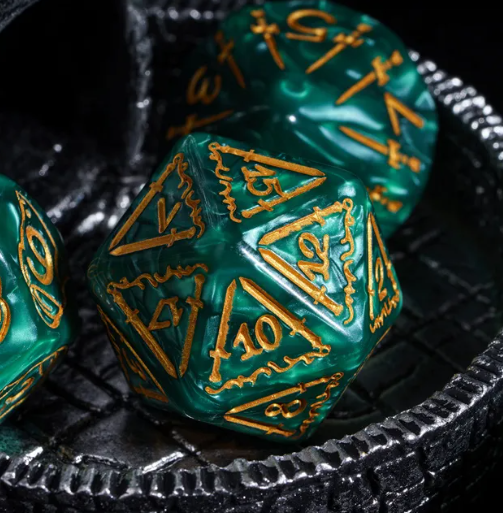 Green polyhedral dice with gold numbering on a textured black surface