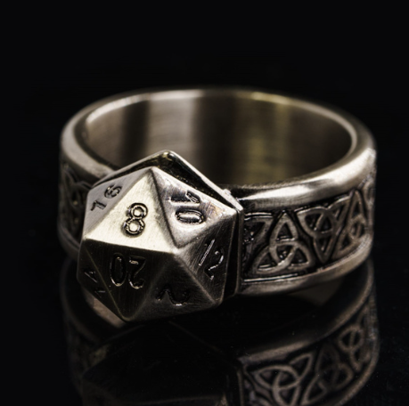 Silver ring with polyhedral die and Celtic knot design on a black background