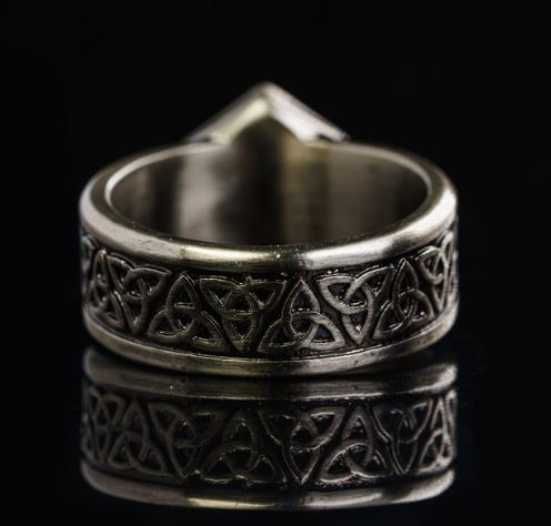 Silver ring with intricate Celtic knot design on a black background