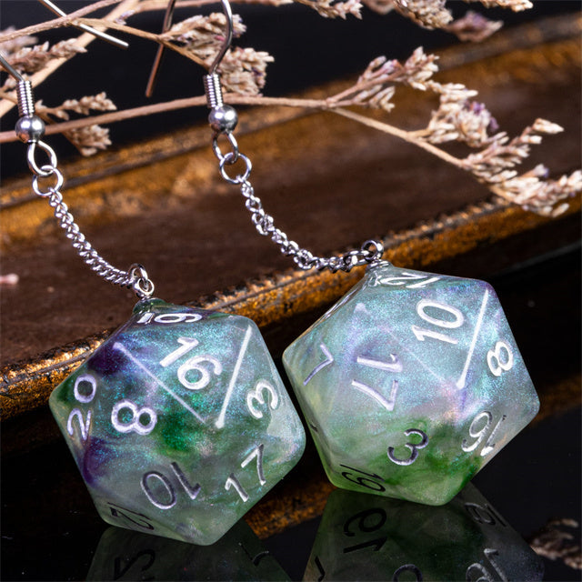 Two green polyhedral dice with number markings on a reflective surface with dried flowers.