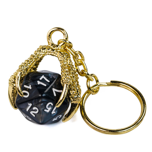 Black polyhedral die keychain with gold metalwork on a white background