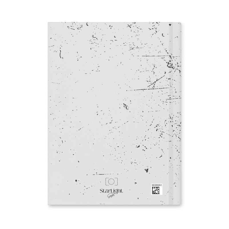 White notebook with black speckled pattern on a white background