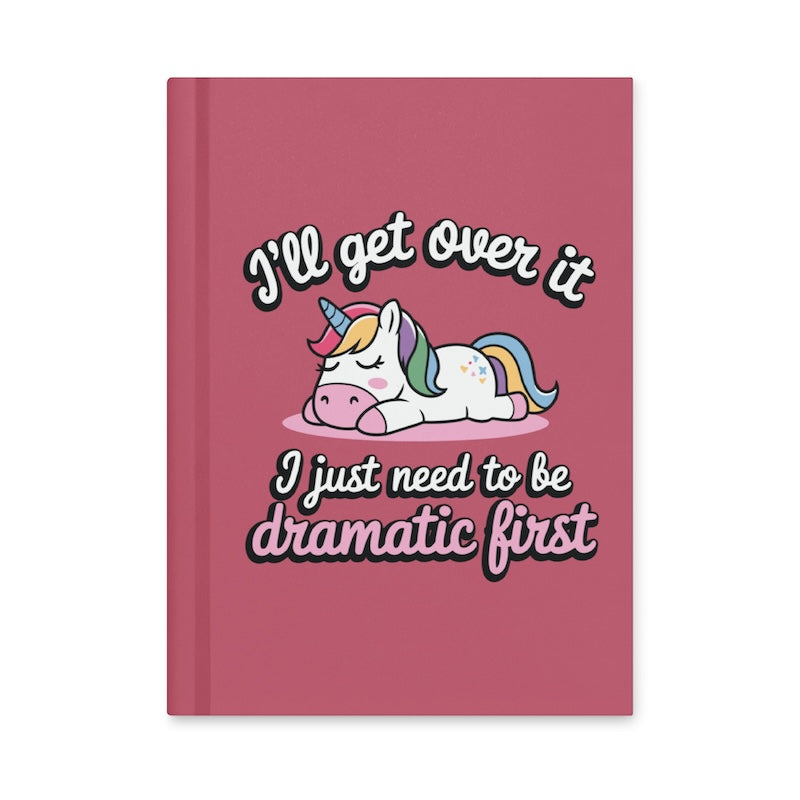 Pink notebook with a unicorn illustration and humorous text on a white background