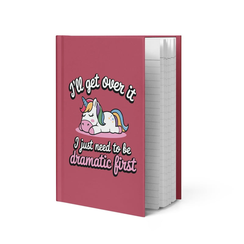 Pink notebook with a unicorn illustration and humorous text on a white background