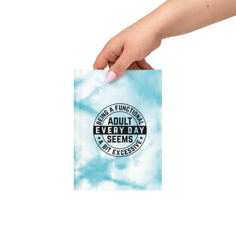 Hand holding a blue tie-dye notebook with text on a white background