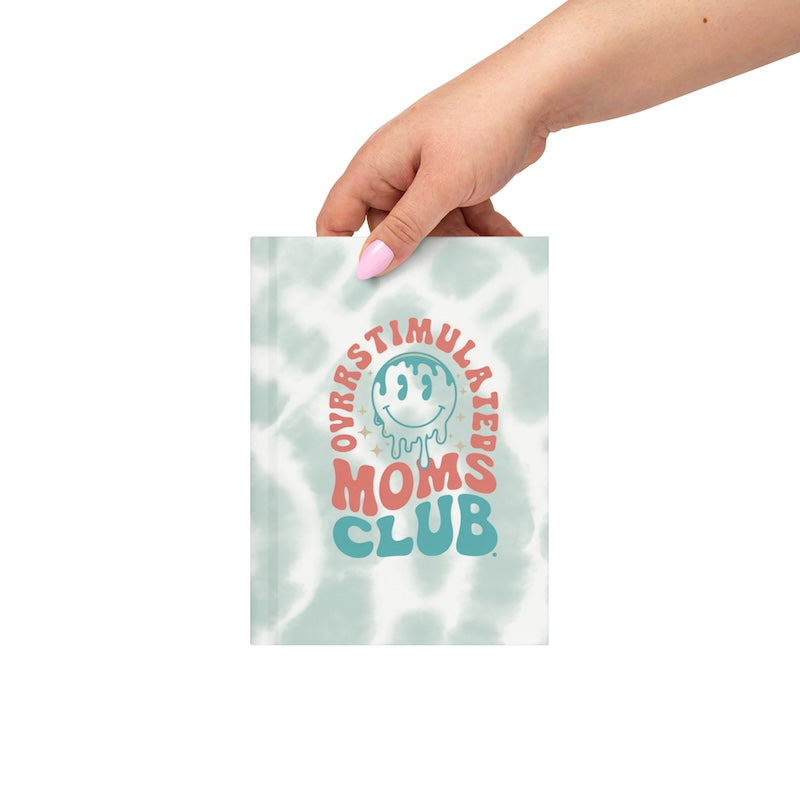 Hand holding a bag with 'Overstimulated Moms Club' text and logo on a white background