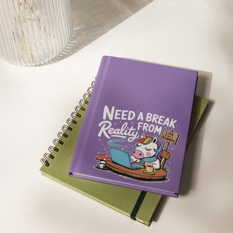 Purple notebook with cartoon unicorn and text 'Need a Break from Reality' on a white surface.