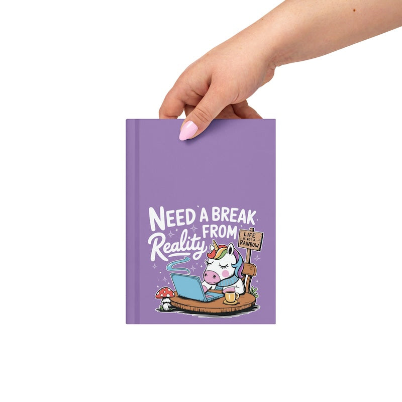 Purple notebook with a unicorn illustration and text, held by a hand on a white background