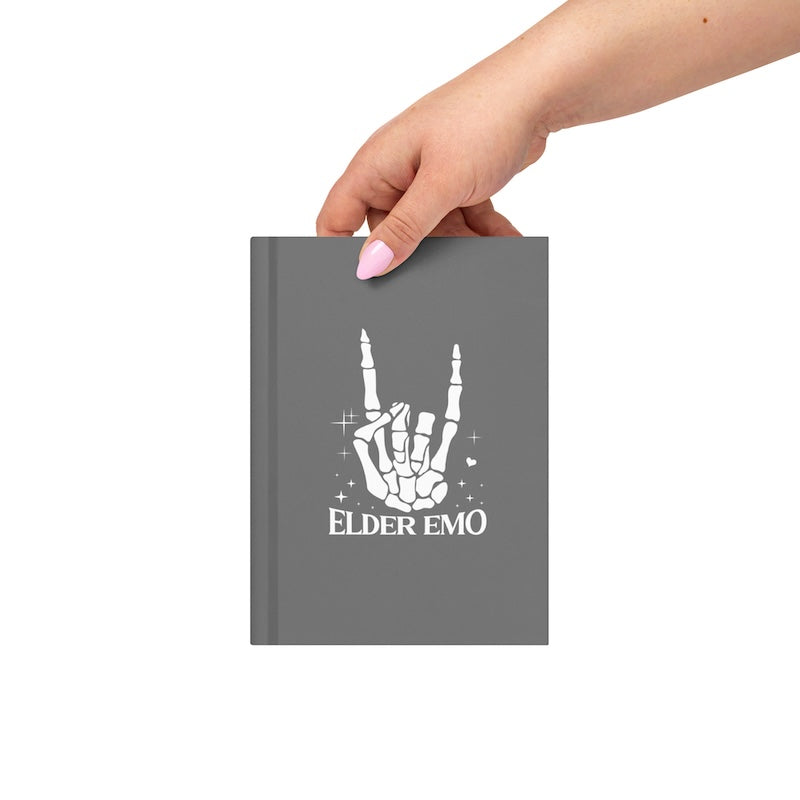 Gray notebook with 'Elder Emo' design held by a hand on a white background