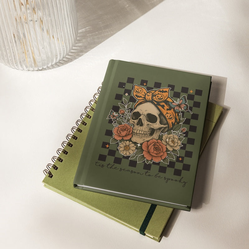 Green notebook with skull and floral design on a white surface