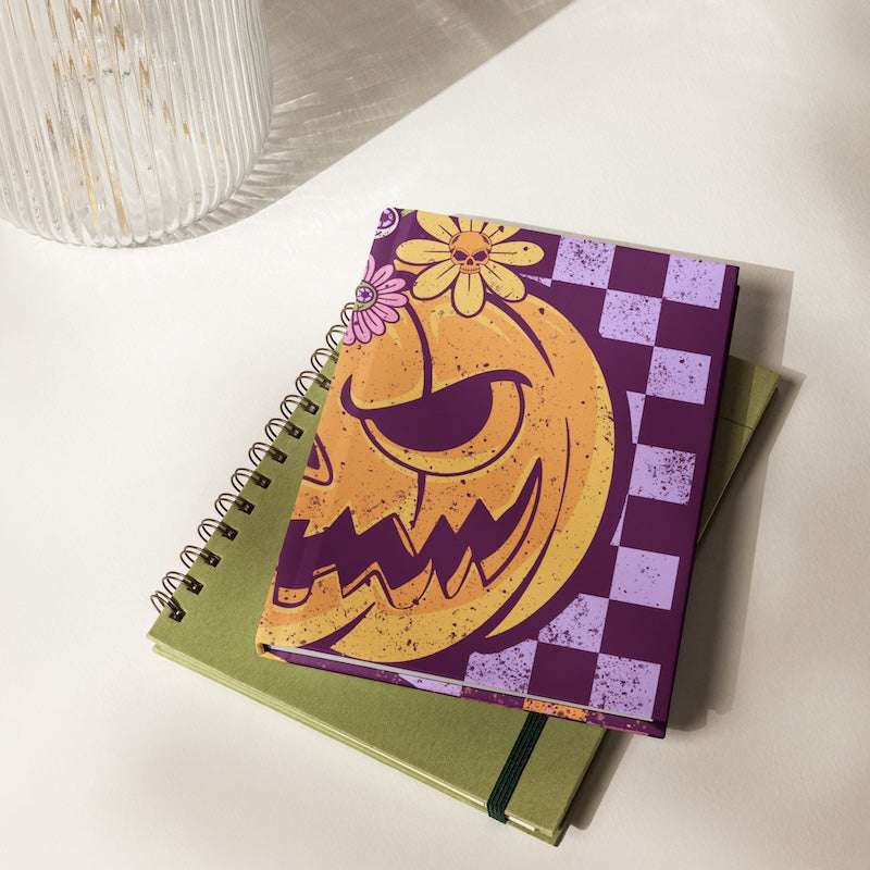 Notebook with a Halloween-themed cover featuring a jack-o'-lantern design on a white surface.