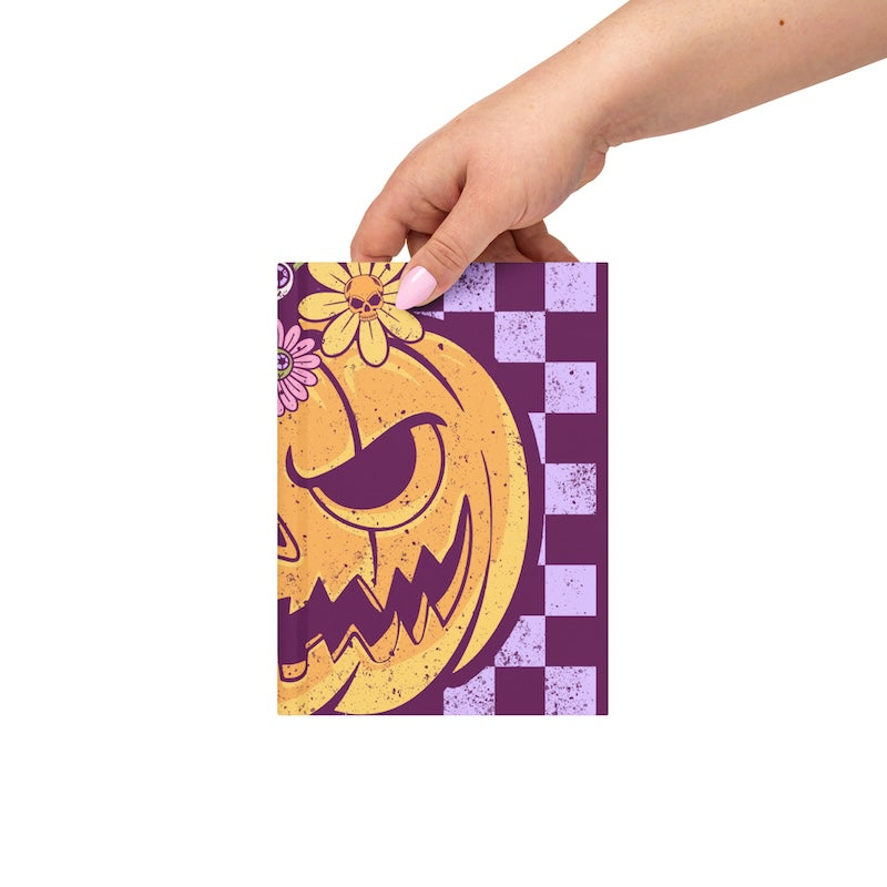 Hand holding a small notebook with a Halloween design on a white background