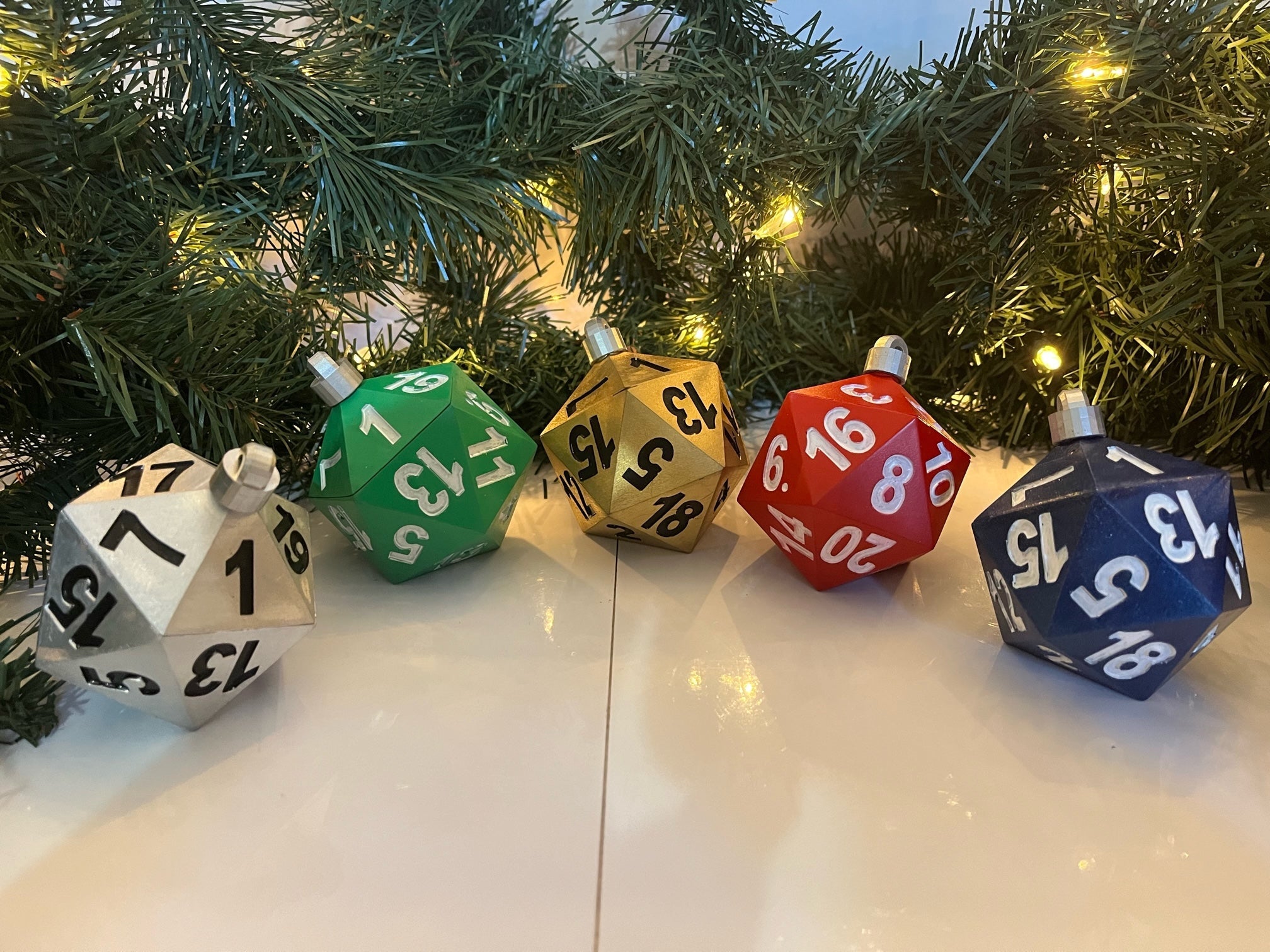 Colorful dice-shaped ornaments on a reflective surface with a Christmas tree in the background.