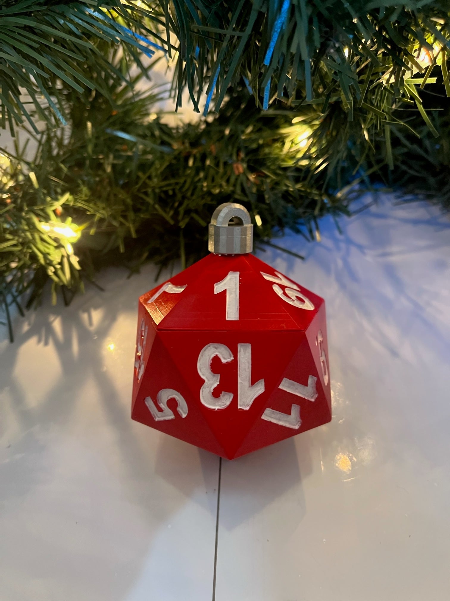 Red die-shaped Christmas ornament with white numbers on a Christmas tree.
