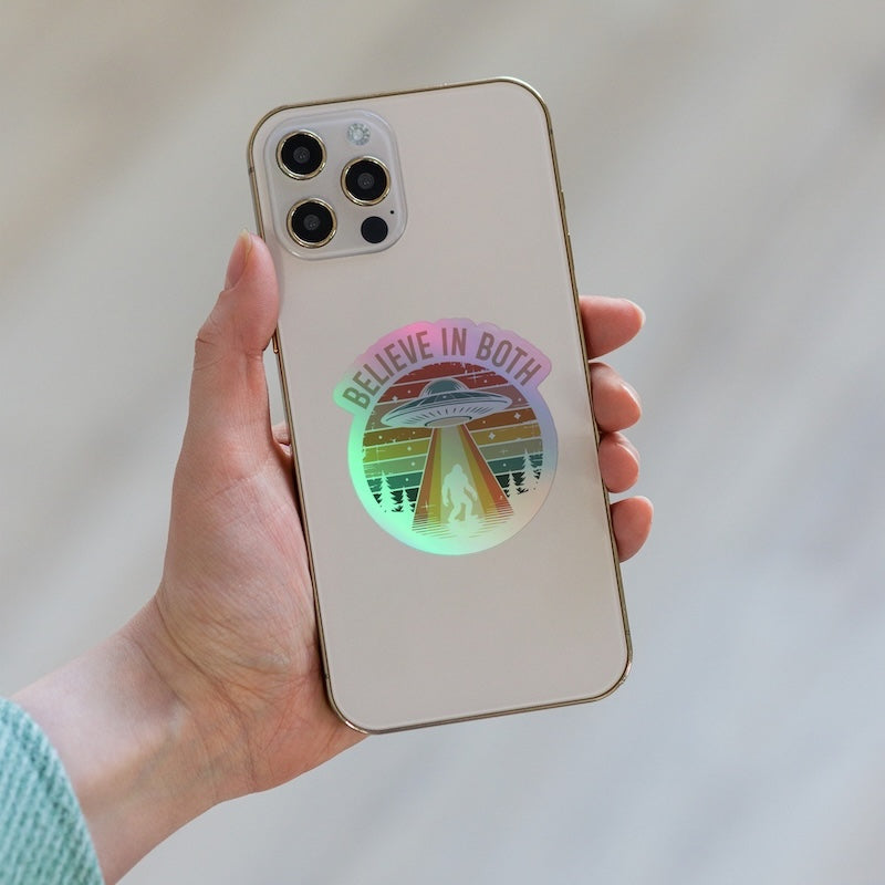 Phone case with 'Believe in Both' design held by a hand against a neutral background