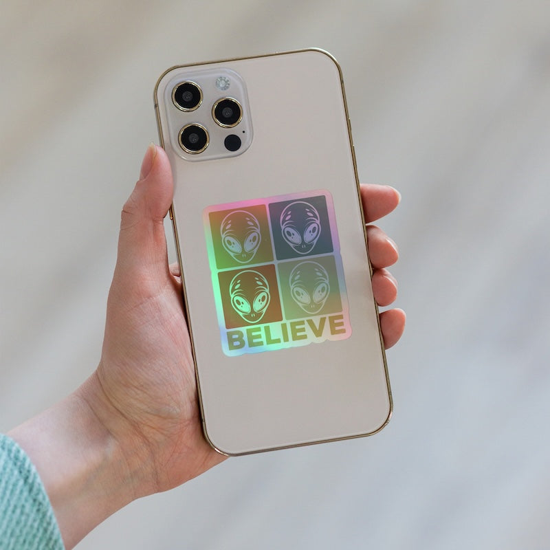 Phone case with alien design and 'BELIEVE' text held by a hand