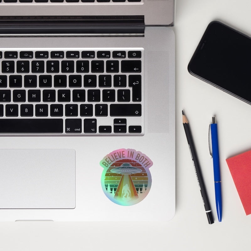 Laptop with a sticker, phone, and pens on a white surface