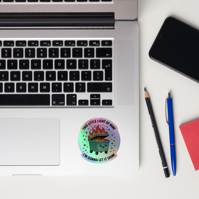 Laptop with a sticker, phone, and pens on a white surface