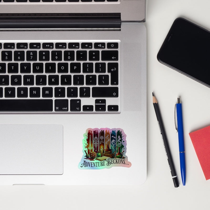 Laptop with a 'Adventure Beckons' sticker, phone, pencil, pen, and notebook on a white surface