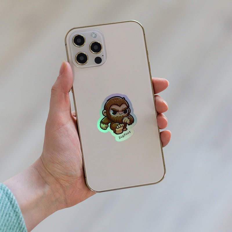 Hand holding a phone with a cartoon monkey sticker on the back