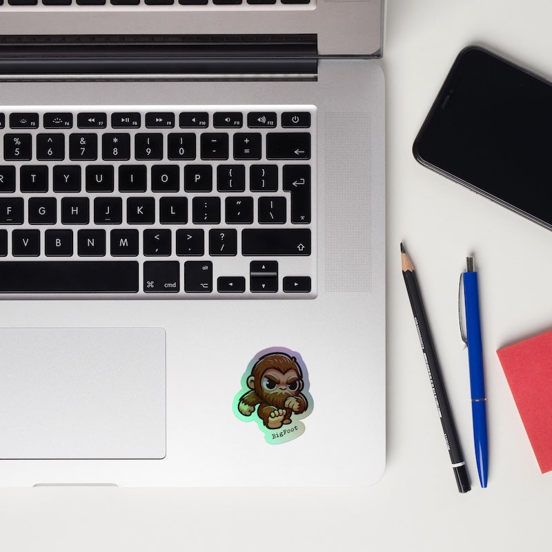 Laptop with a sticker, phone, and pens on a white surface