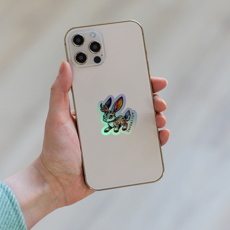 Hand holding a phone with a glowing sticker on a light background